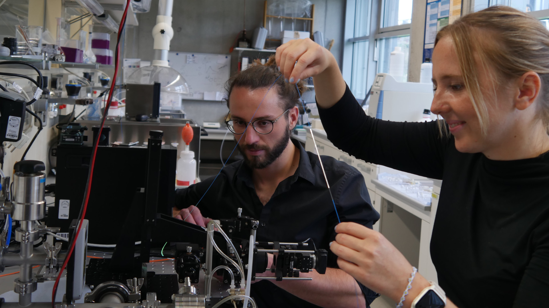 Doktorand Valerius Abb und Masterstudentin Verena Lechner justieren den optischen Aufbau zur Messung der MOF-beschichteten Glasfaser.