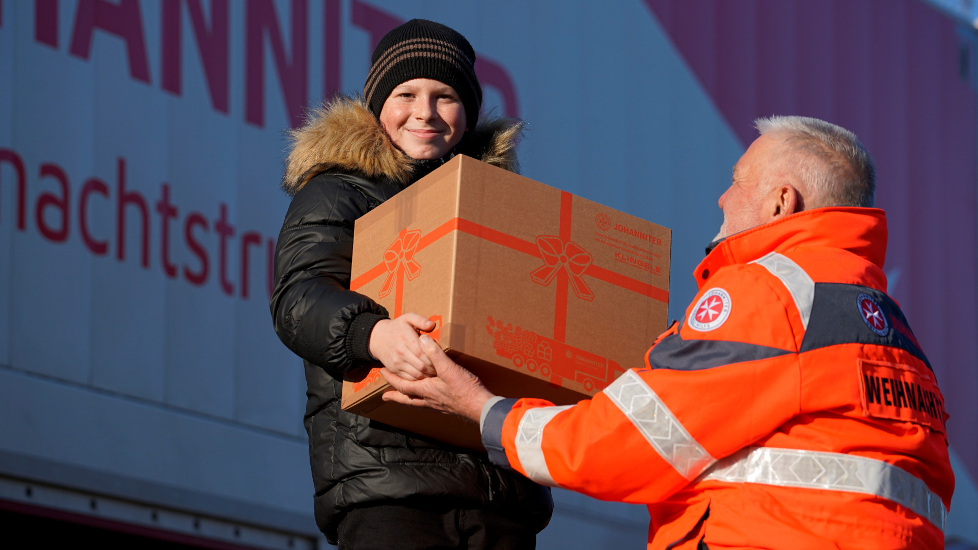 Kind nimmt Paket von Johannitern an