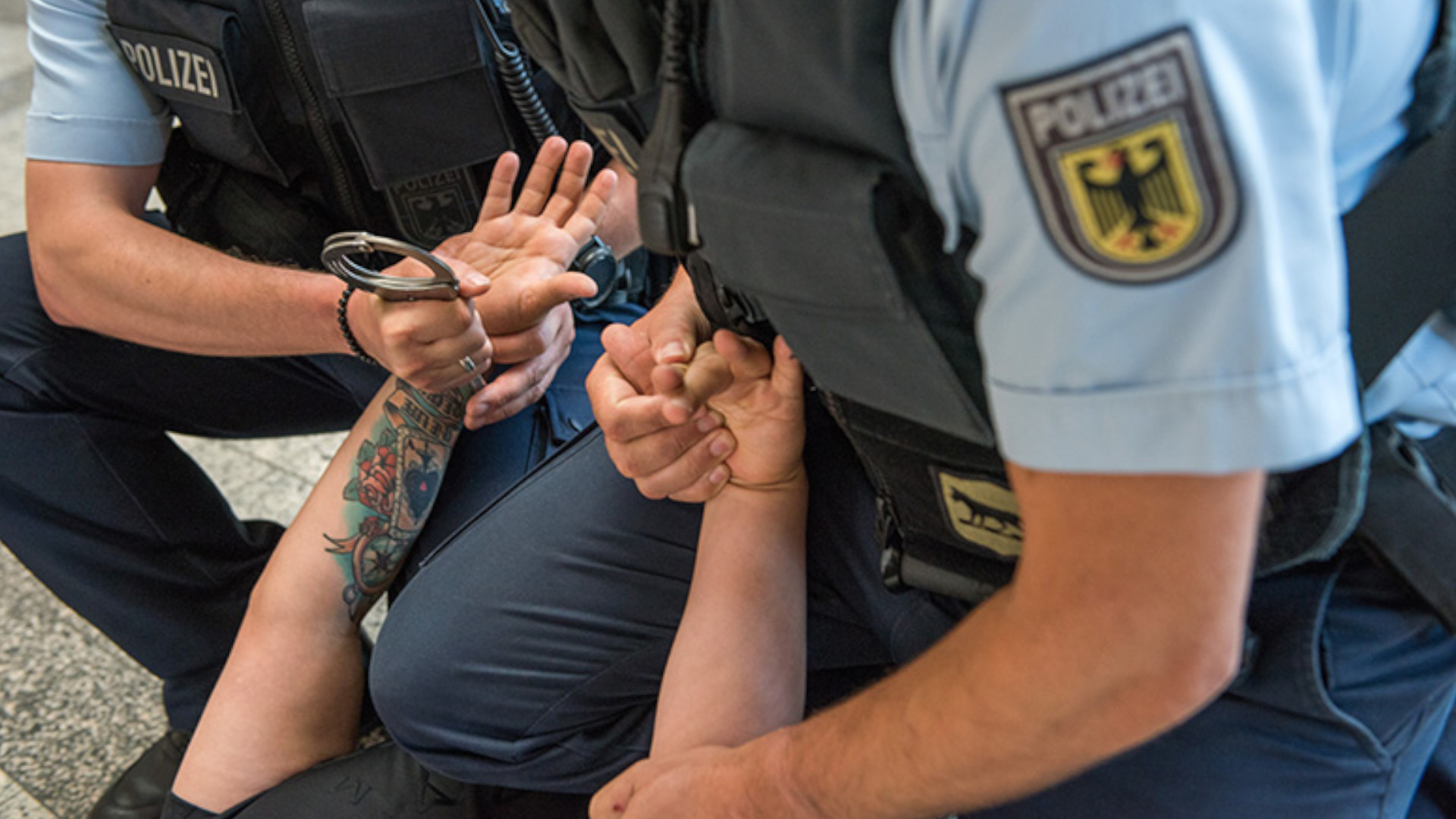 Symbolbild: Polizisten legen einem Mann Handschellen an