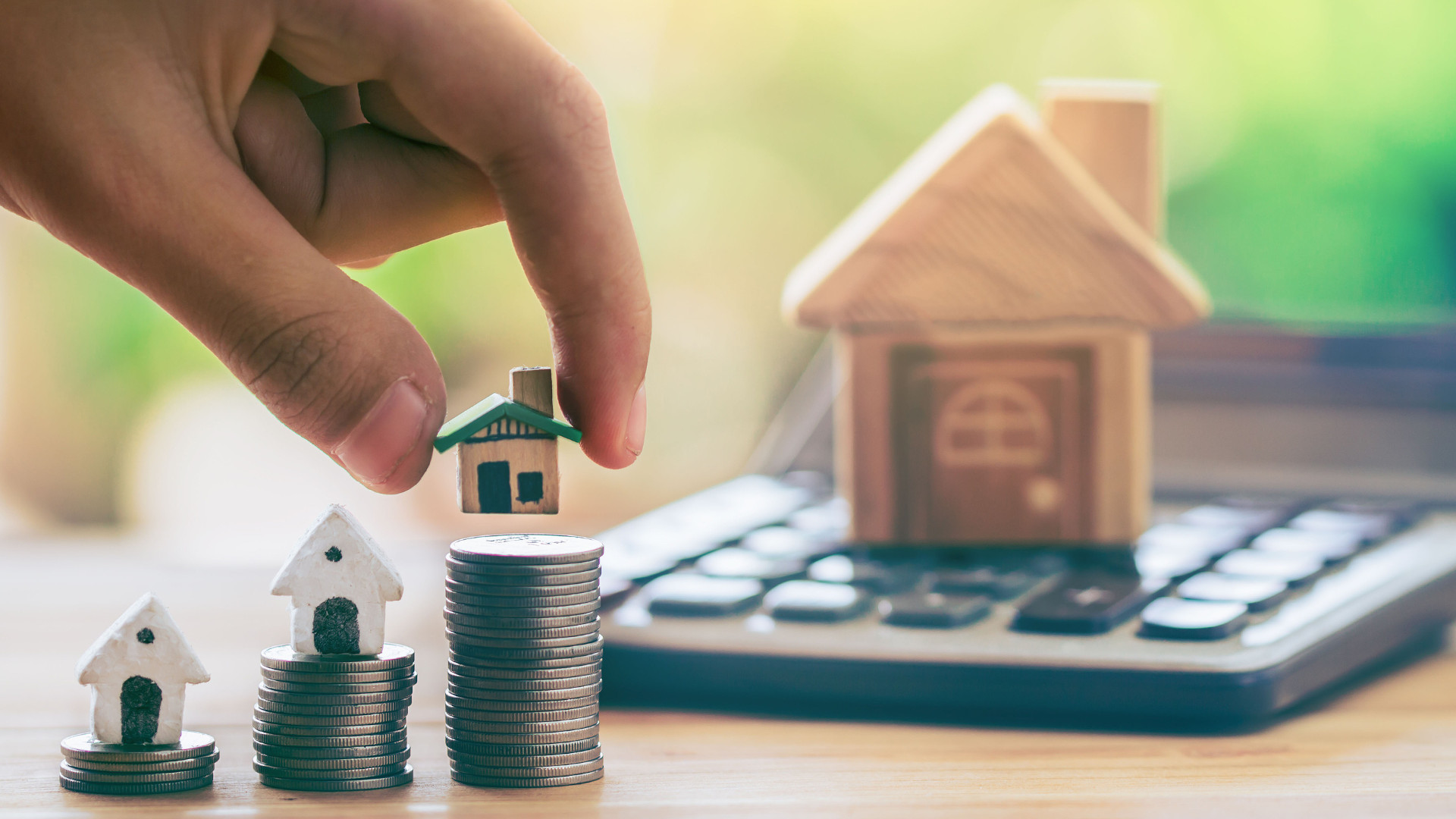 Symbolbild: Kleine Häuser werden auf Münzen gestapelt