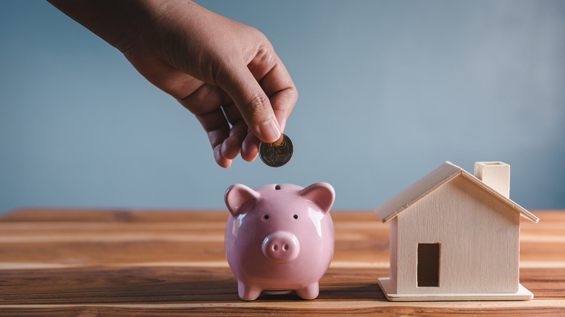 Symbolbild: Sparschwein steht neben einem kleinen Haus