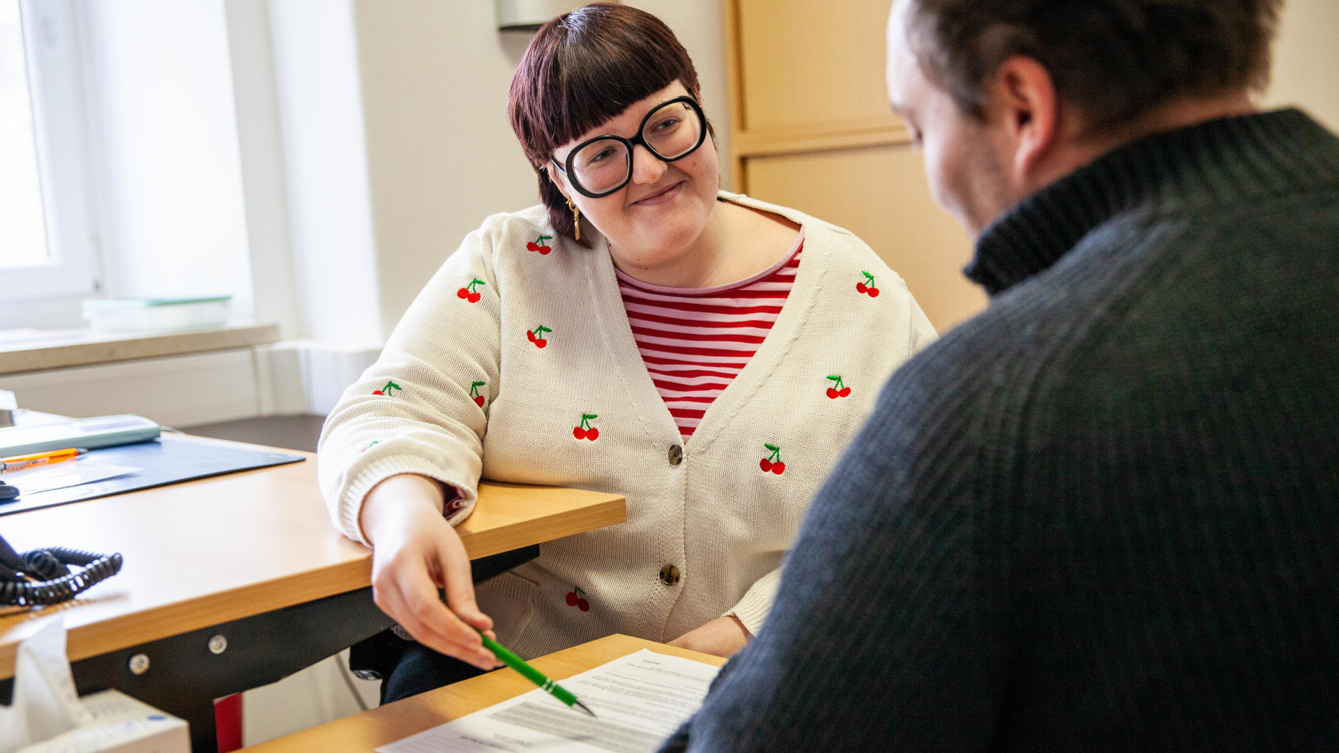 Damit die Bewohner der Caritas Notunterkunft ihr Wahlrecht ausüben können, unterstützen die Mitarbeitenden sie bei Bedarf beim Ausfüllen des Wahlantrags. Pauline Jahn bespricht den Antrag mit einem Klienten.