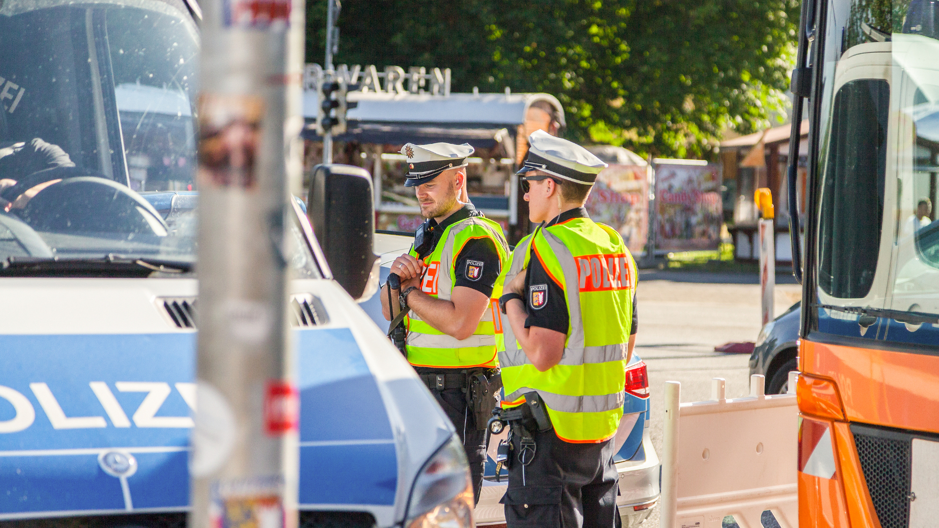 Symbolbild: Zwei Polizisten stehen vor einem Streifenwagen