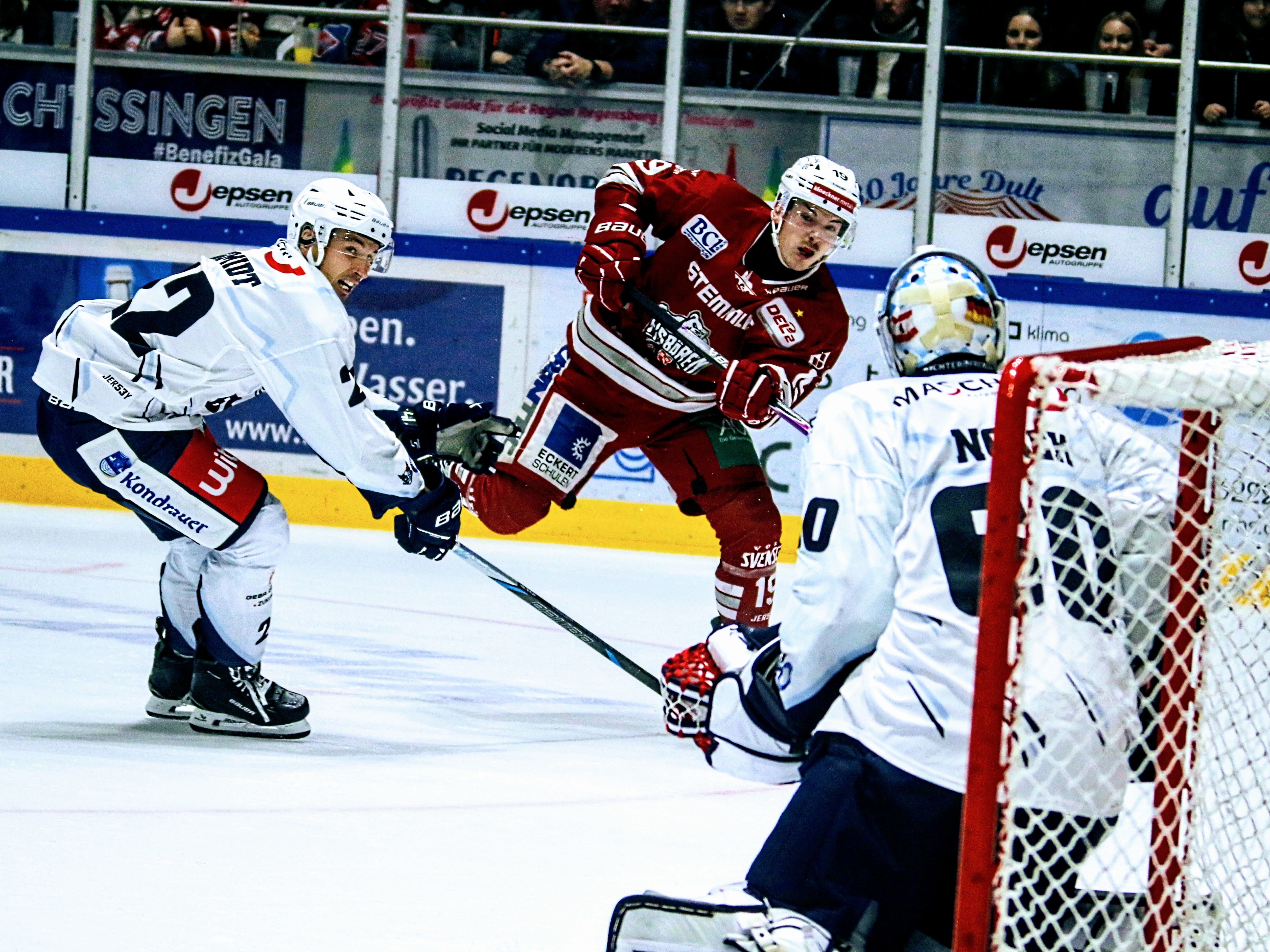Den Eisbären Regensburg um Stürmer Constantin Ontl (Mitte, rotes Trikot) steht das vierte Oberpfalz-Derby der laufenden Saison gegen die Blue Devils Weiden (rechts Torhüter Felix Noack) am Freitagabend in der Donau-Arena bevor