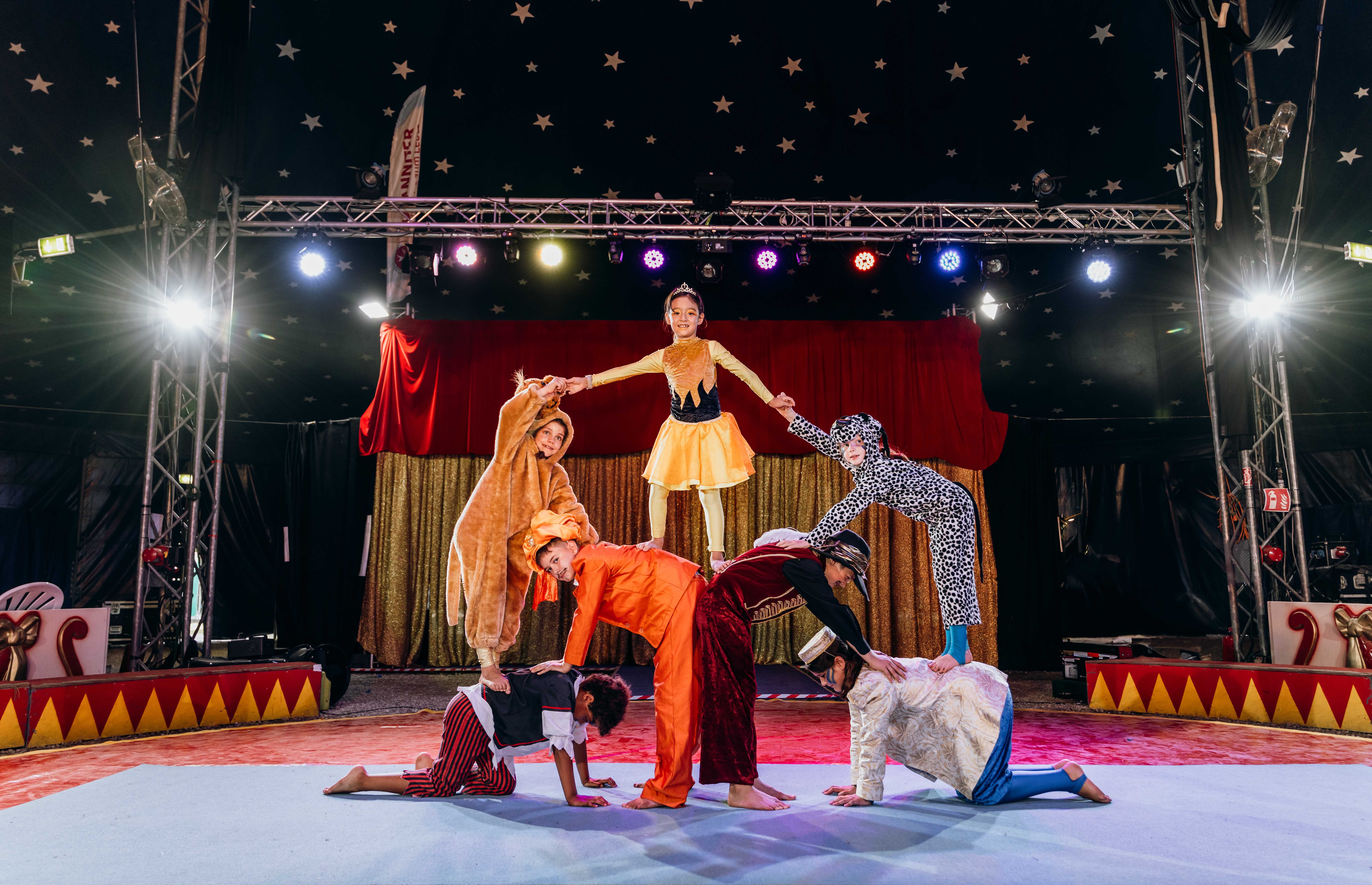 In kunterbunten Kostümen balancieren sich die Kinder einander auf einer Pyramide.