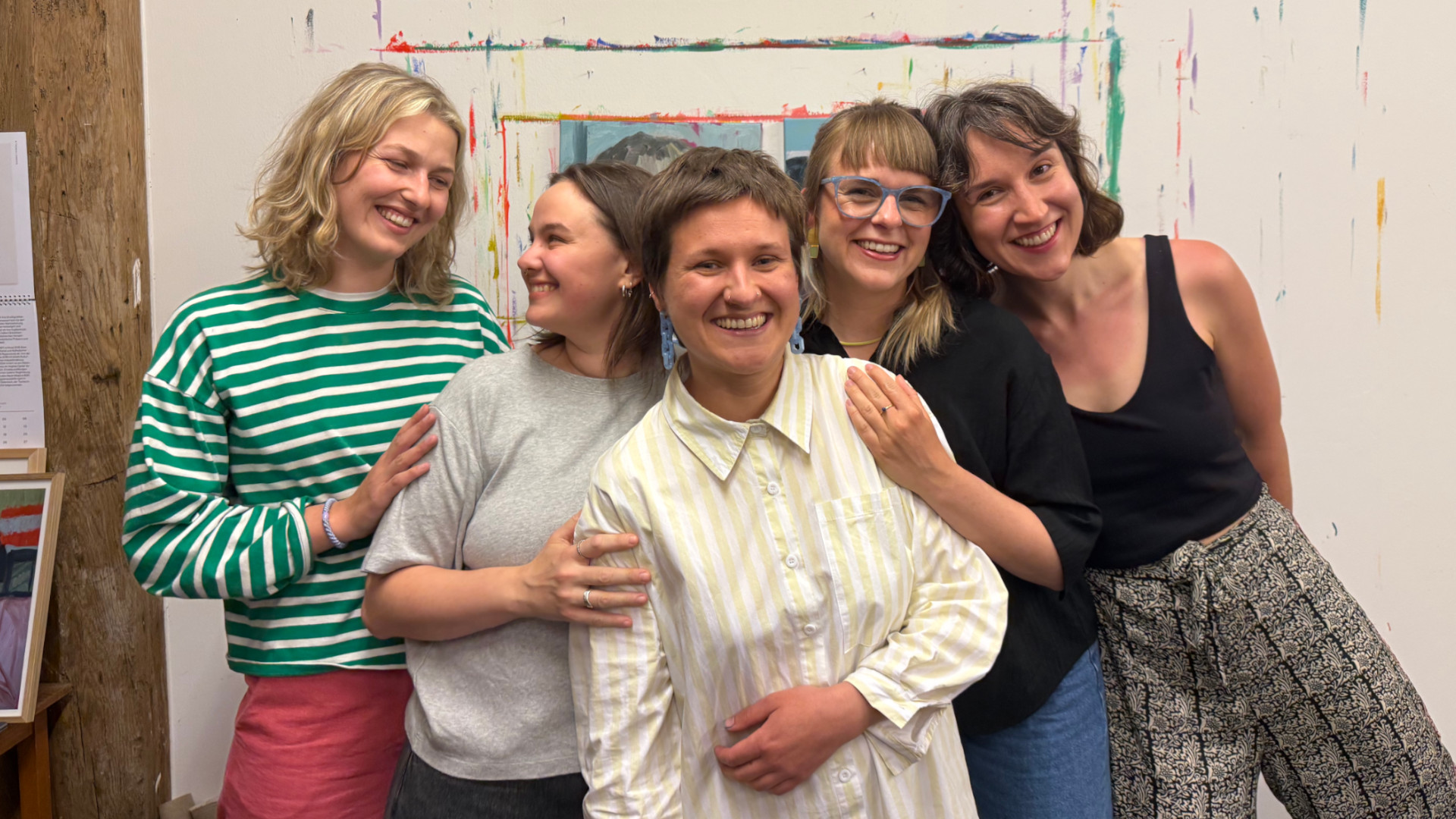 Die fünf Künstlerinnen posieren vor einer bunten Wand