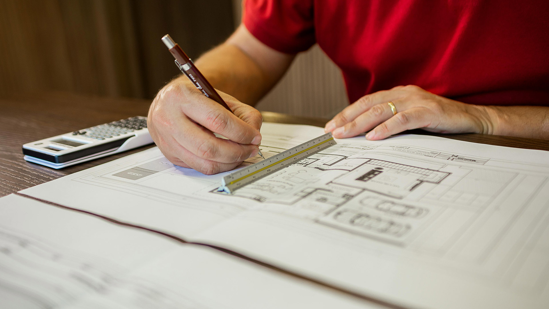 Mann zeichnet Entwurf am Schreibtisch