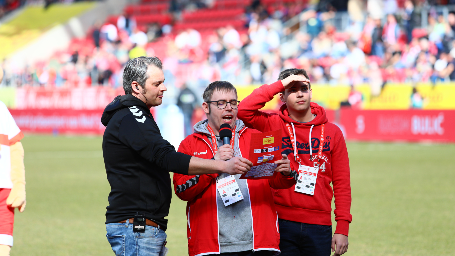 drei Männer, einer mit Mikrofon, Spieltag ohne Hindernisse