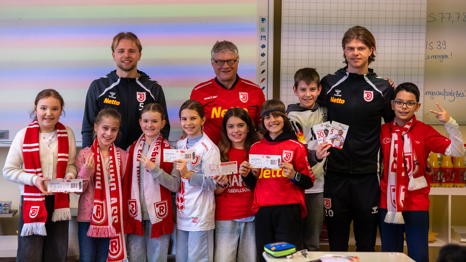 Jahn-Spieler posieren mit Kindern im Klassenzimmer