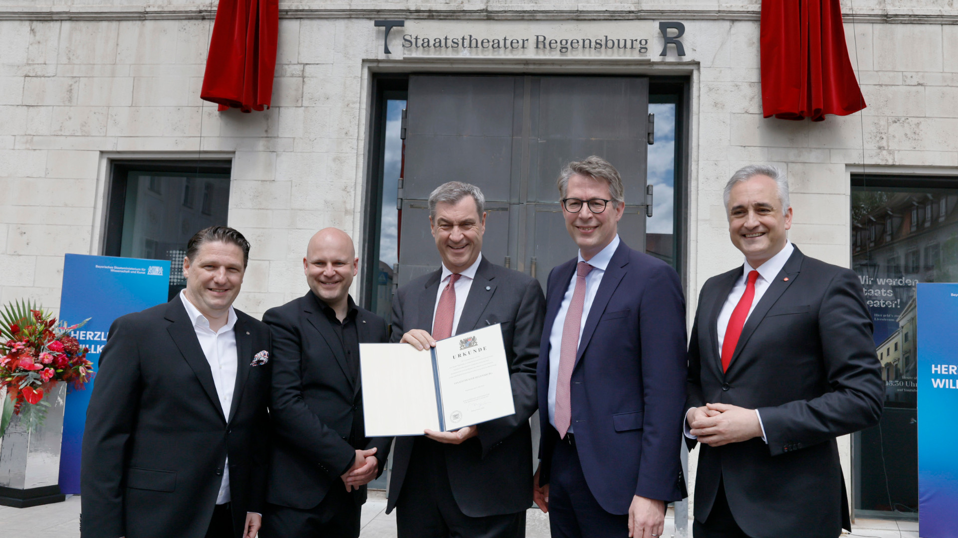 Vor dem Theater unter dem Logo: v.l.n.r:  Kaufmännischer Direktor Dr. Matthias Schloderer, Intendant Sebastian Ritschel, Ministerpräsident Dr. Markus Söder, Kunstminister Markus Blume, Oberbürgermeister Dr. Thomas Burger