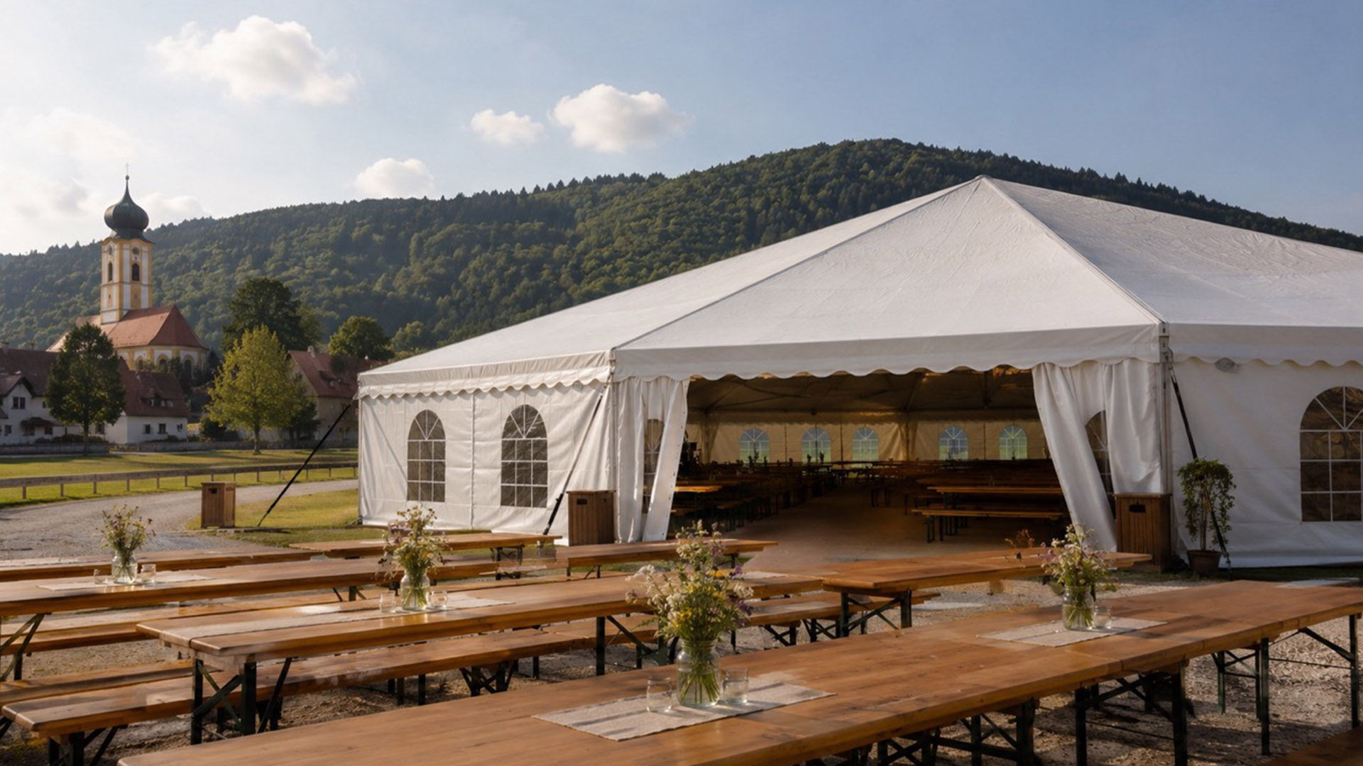 Festzelt mit Biertischen davor und Kirche im Hintergrund