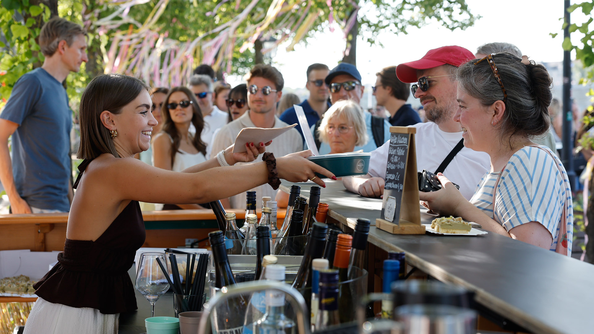 Erster Brückenaperitivo: Junge Frau hinter der Bar  reicht Gästen eine Schüssel.