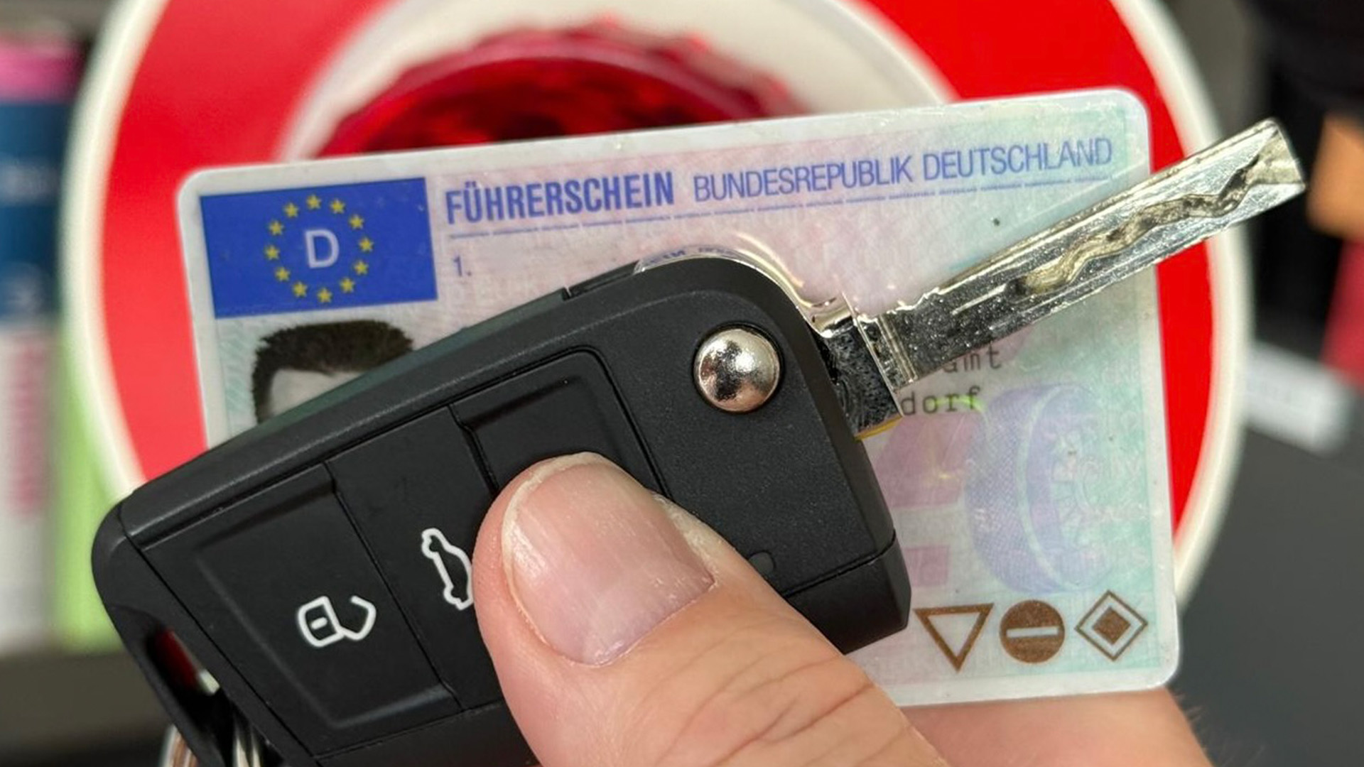 Symbolbild: Führerschein und Autoschlüssel vor Warnhinweisschild