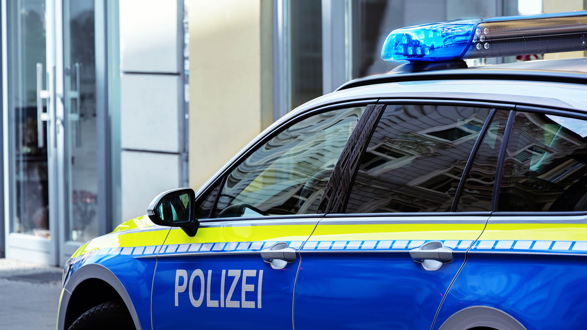 Streifenwagen der Polizei vor Gebäude