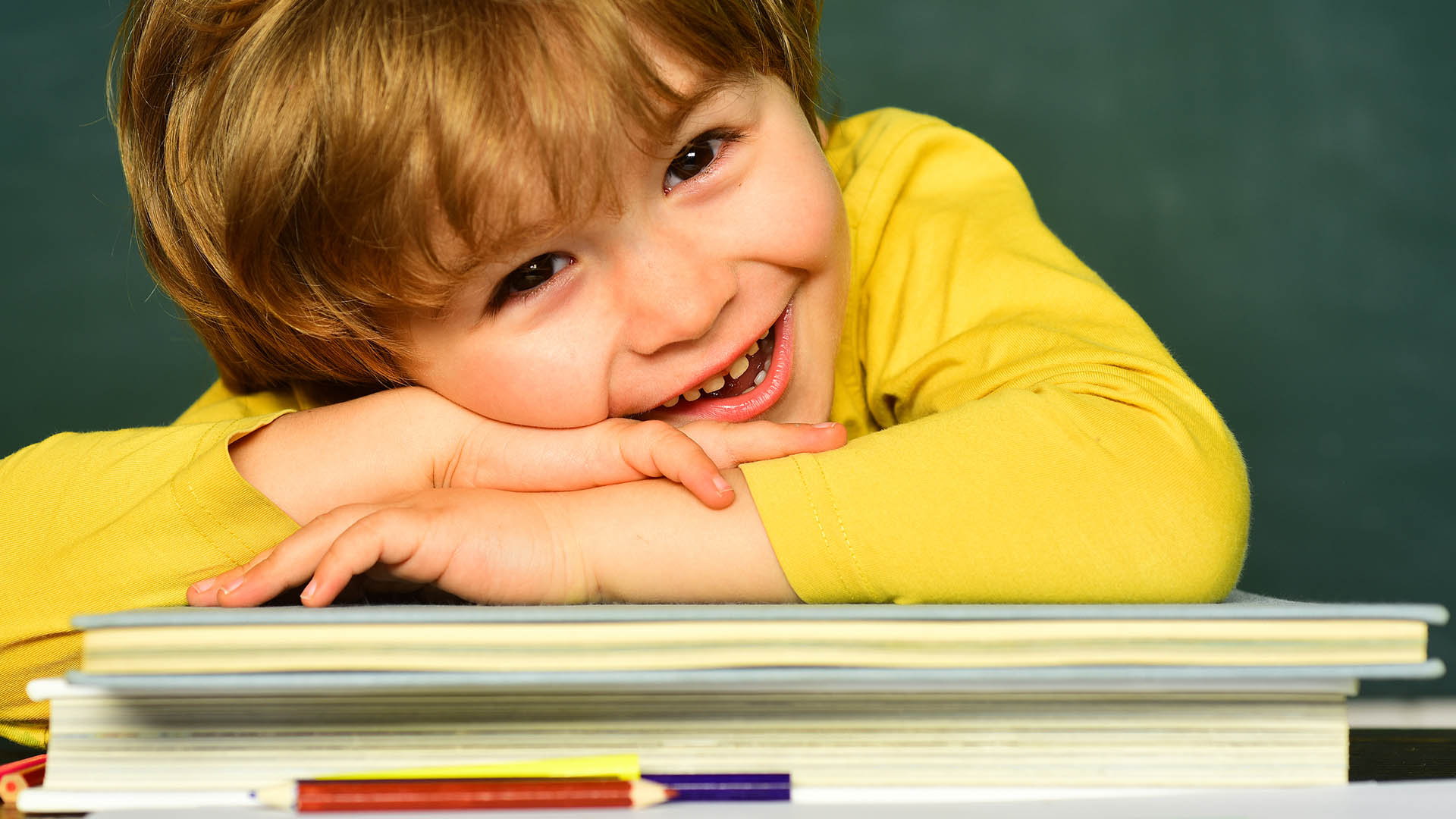 Lächelnder Schüler, der seinen Kopf auf Schulbücher legt.