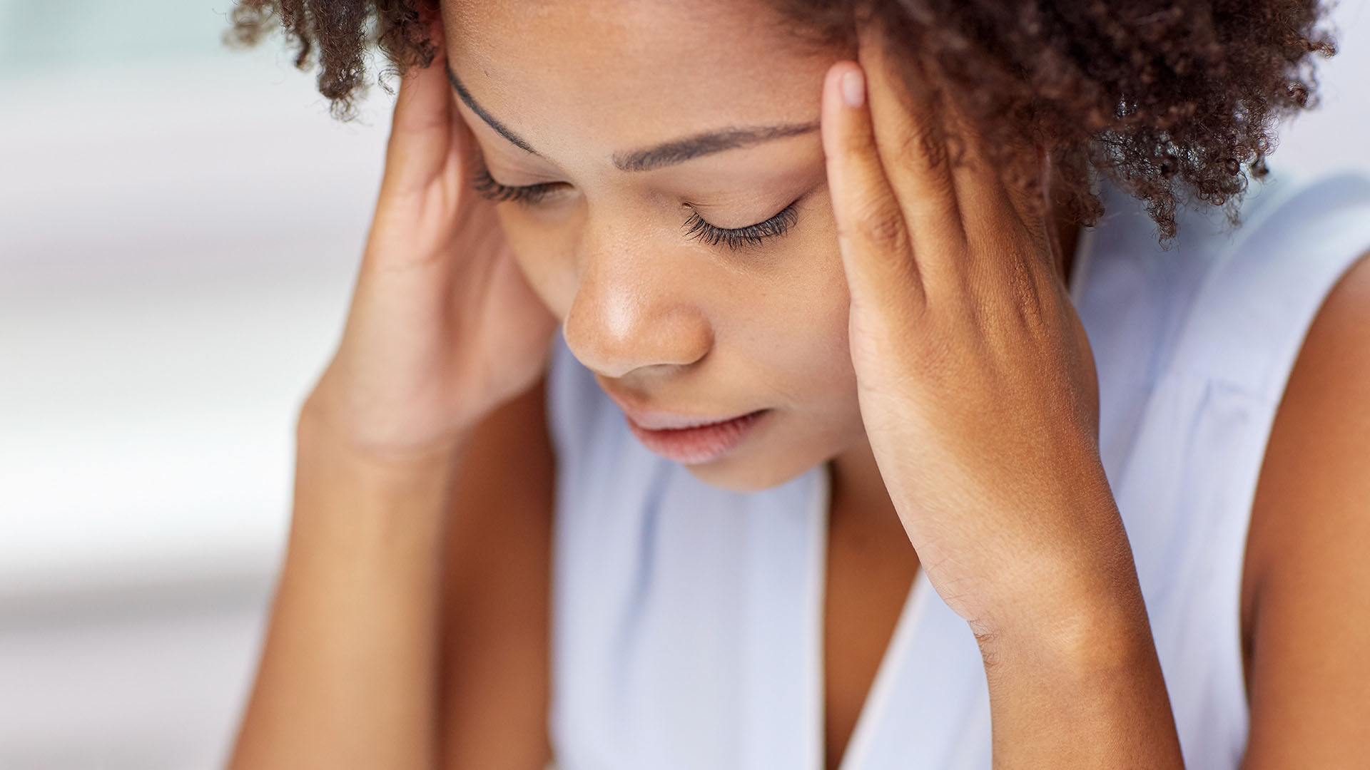 Thema Stress: Frau massiert sich mit beiden Händen die Schläfen