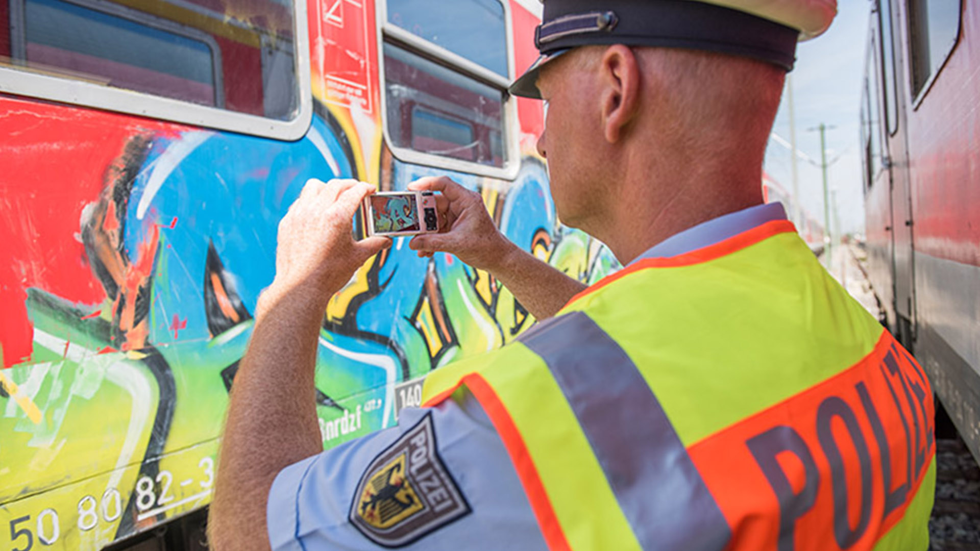 Symbolfoto Bundespolizei: Polizist fotografiert Graffiti auf einem Zug