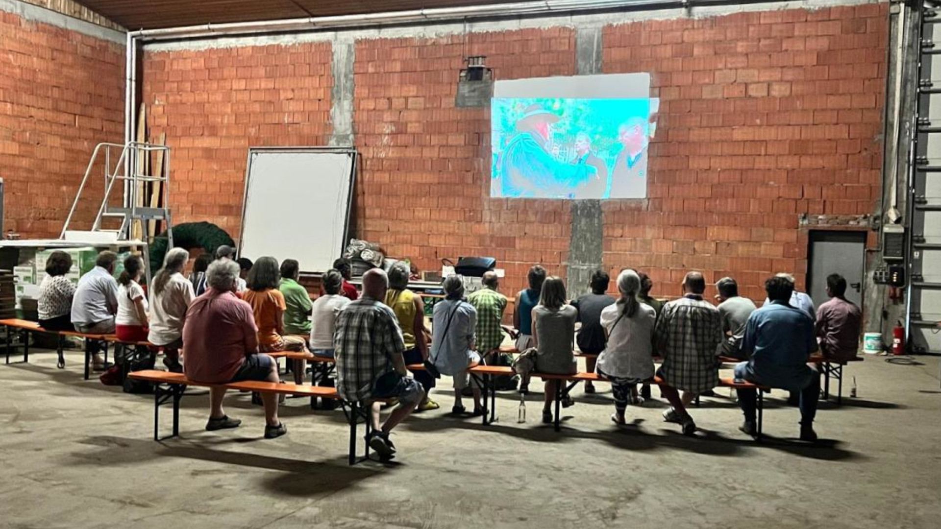 Bauernhofkino in Rohr: Mehrere Personen sitzen in Bauernhofgebäude und sehen einen Film.