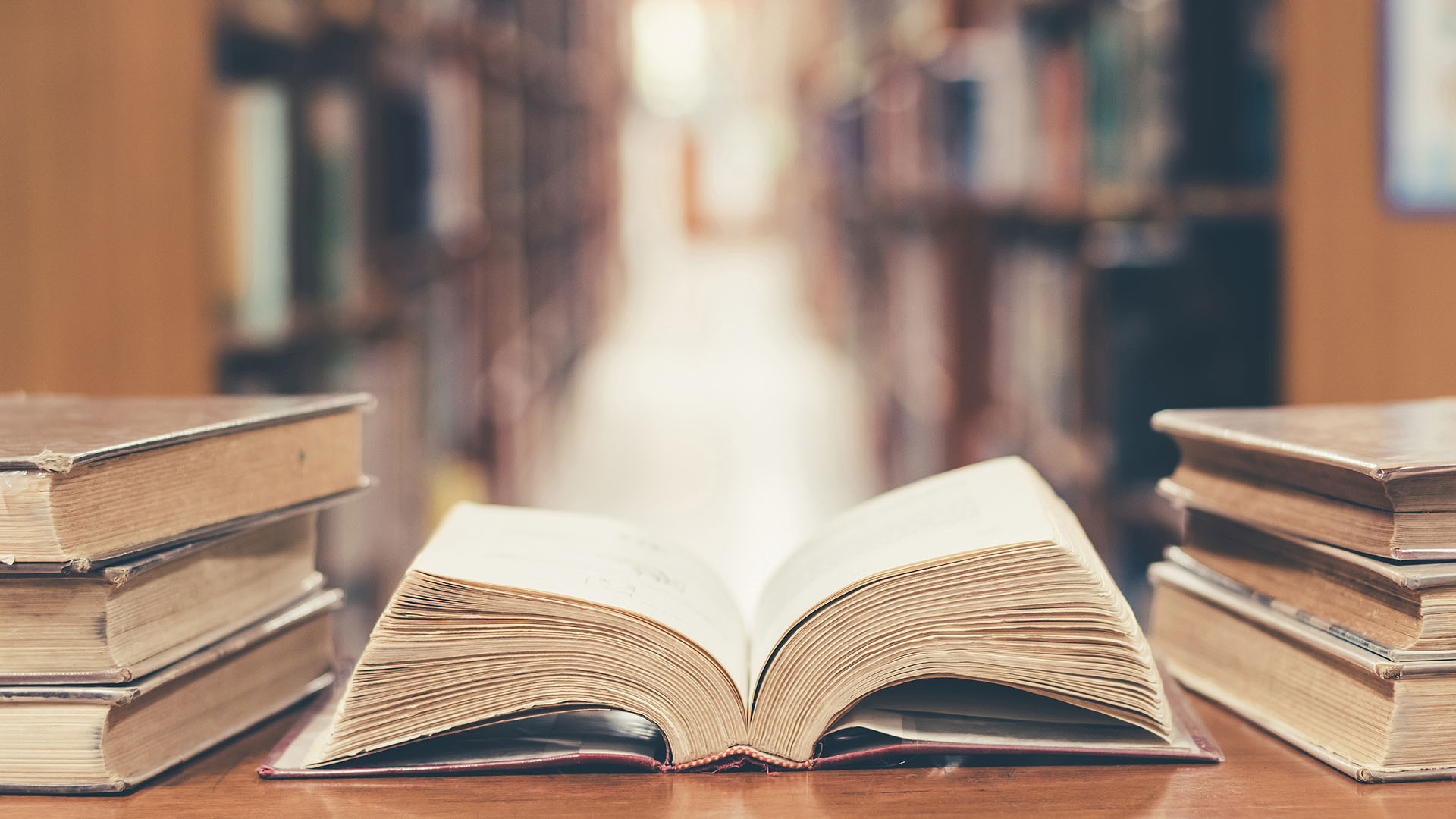 Bücherei mit aufgeklapptem Buch im Vordergrund