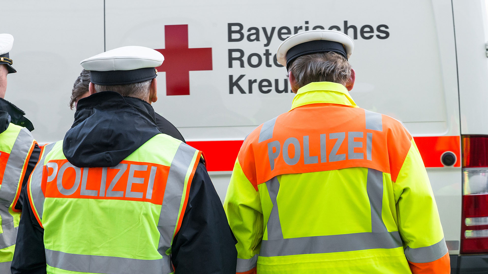 Mehrere Polizisten, dahinter ein Krankenwagen.