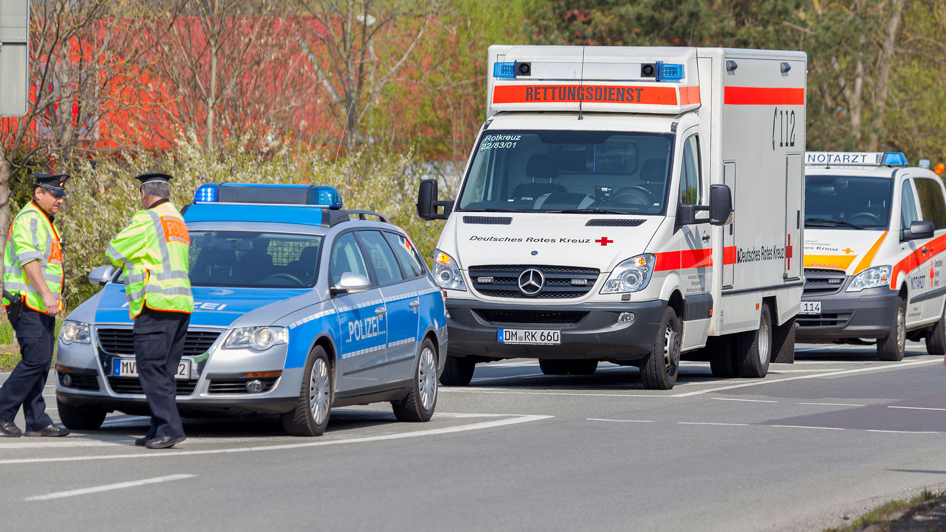 Streifenwagen der Polizei mit Polizisten, dahinter Rettungsdienst und Notarzt.