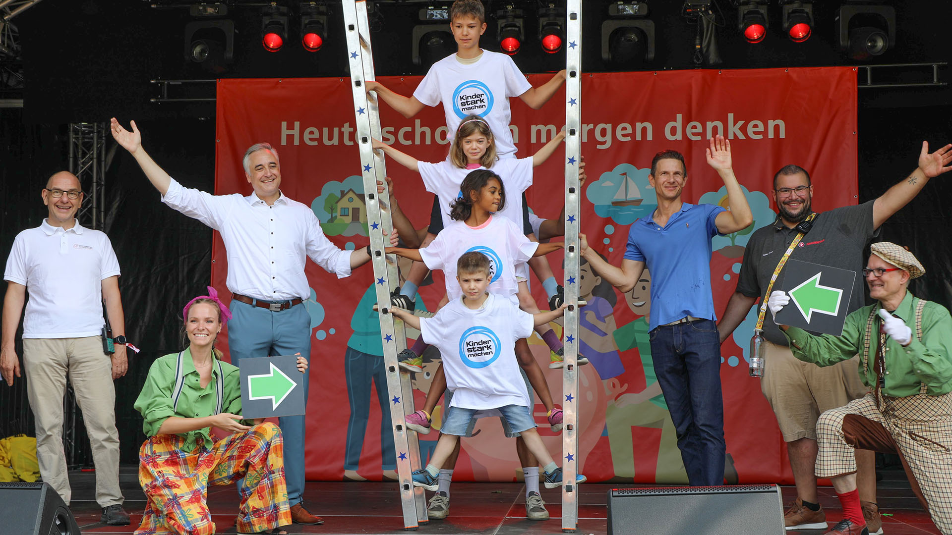 Michael Quast (Stadtmarketing Regensburg), Oberbürgermeister Dr. Thomas Burger, Helmut Handeder (Sparkasse Regensburg) und Tobias Karl (Johanniter Ostbayern) gemeinsam mit Stephan Zenger (Clowntheater Spectaculum), einer Clownin sowie Kindern der Initiative „Kinder stark machen" auf der Bühne.