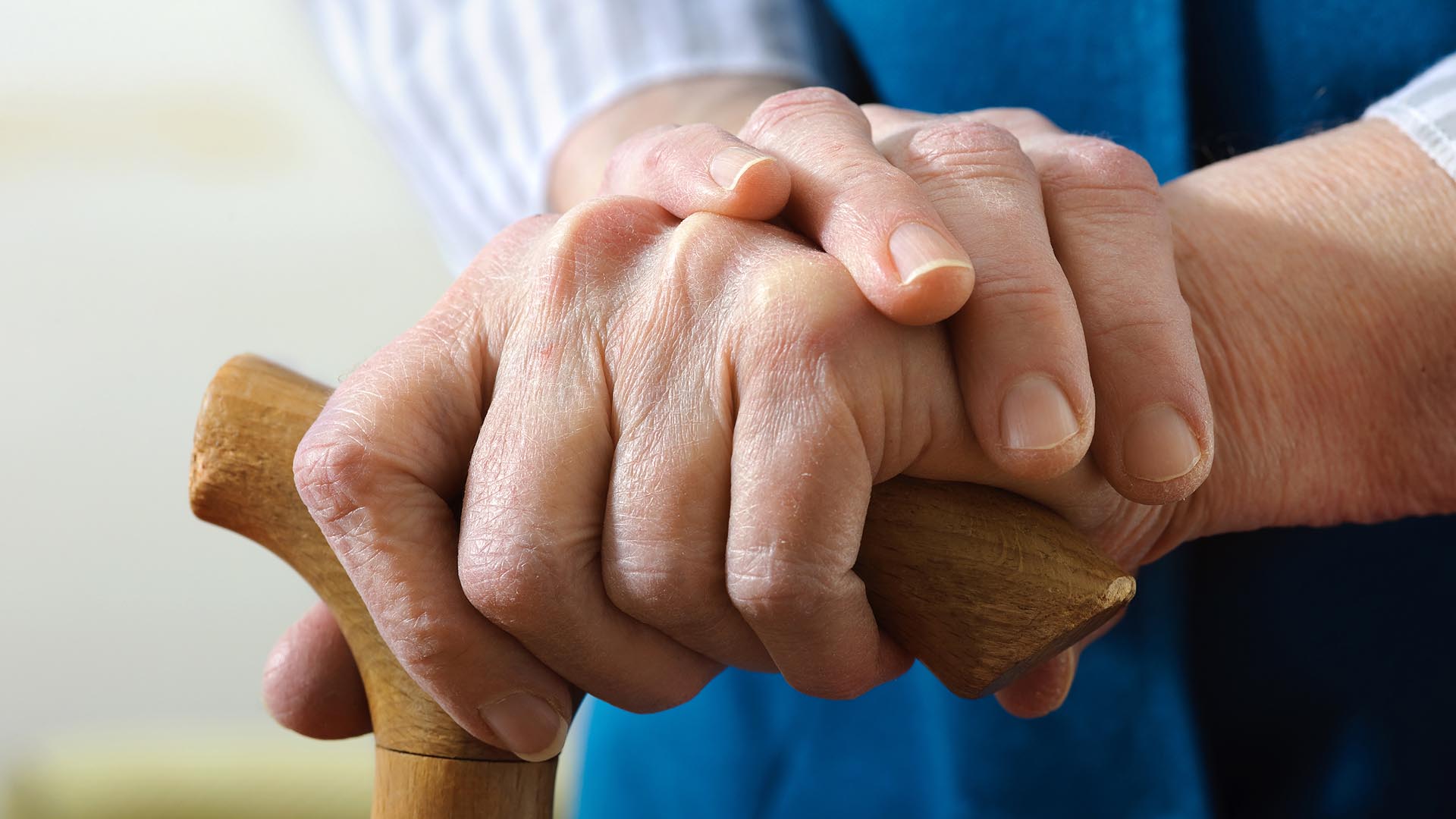 Mann legt seine Hand auf die Hand eines Angehörigen mit Gehstock