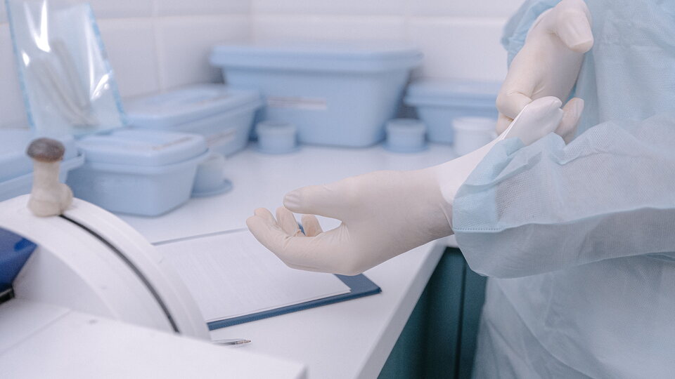 Gesundheitspersonal zieht sterilen Handschuh an